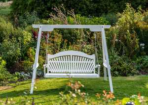 Painted garden swing seat set amongst lawn and flower bed