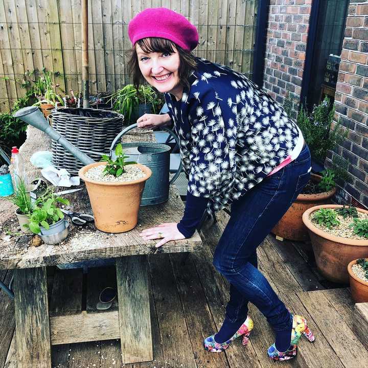Ann-Marie holding a watering can ready to garden in some colourful heels