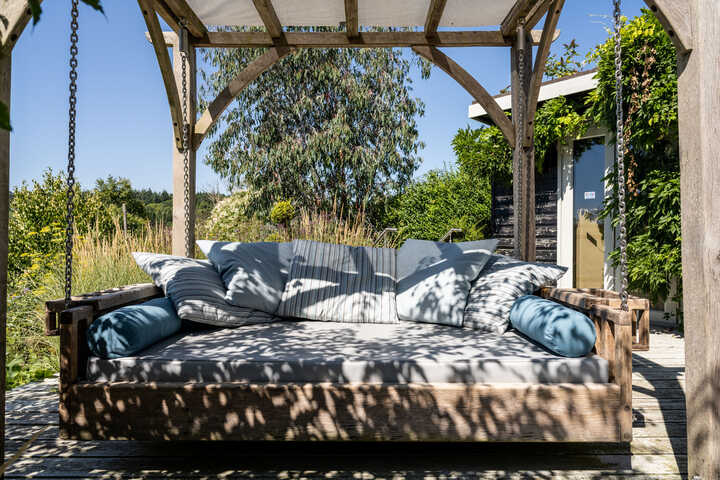 Day bed with drinks holders and cushions in dappled shade