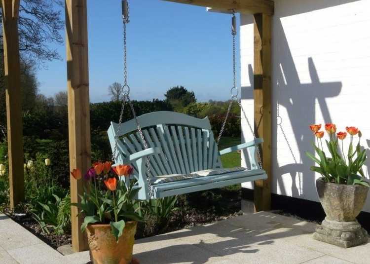 A swing bench hanging from a structure on a patio