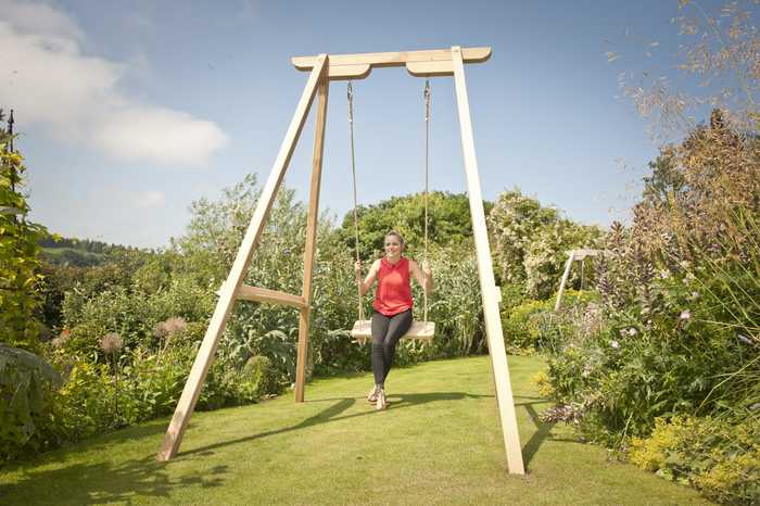 Girl on tall swing frame in garden