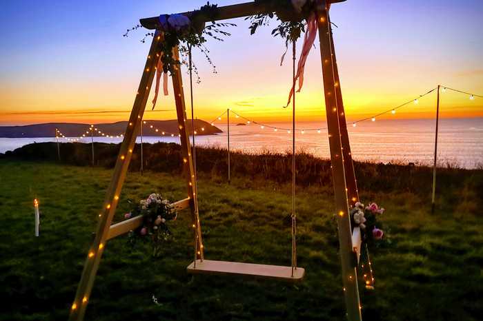 Rope swing and frame with lights overlooking the sea