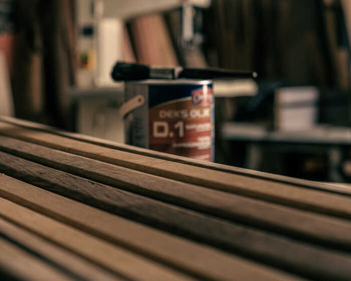 Wooden slats with a can of oil finish and brush in the background.