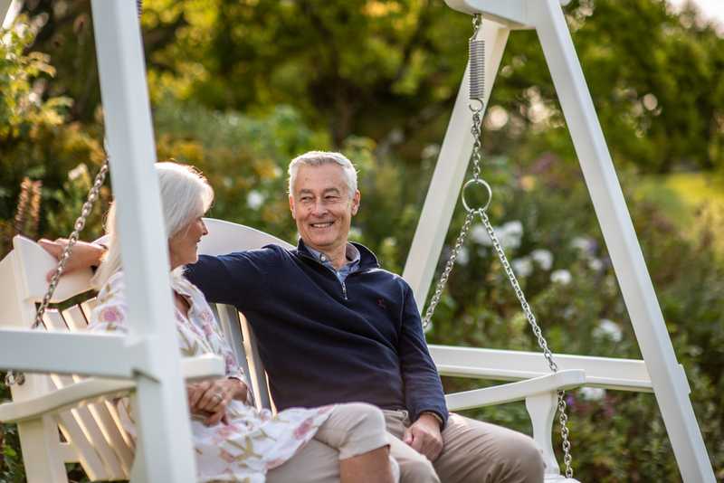 Elderly couple on a painted swing seat in a garden