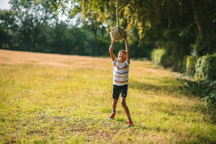 Young child enjoying playing with rope ball swing 