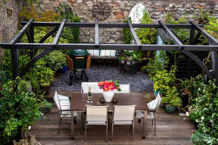 A bespoke pergola above some decking with a laid table underneath