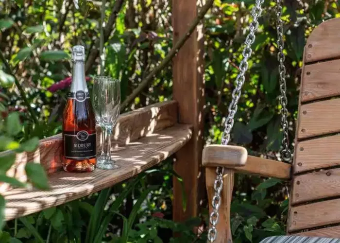 bottle-of-sparkling-rose-and-champagne-flute-on-swing-seat-armrest-1.webp