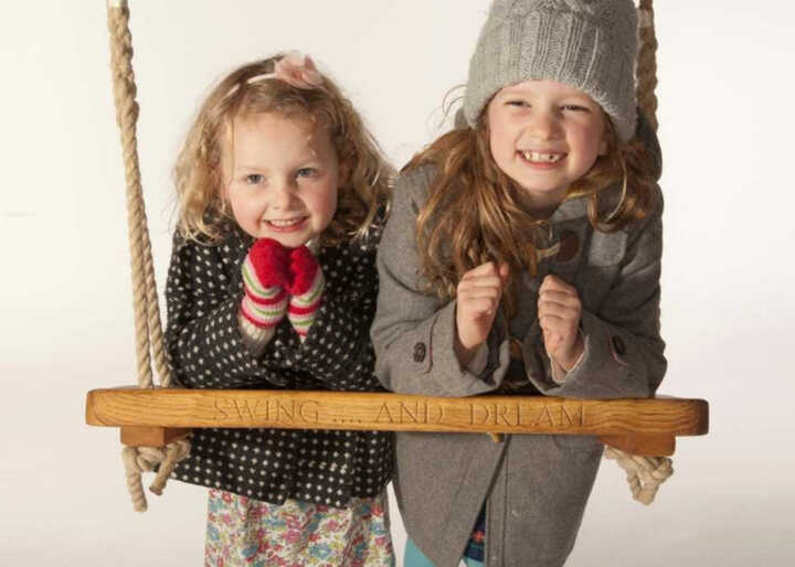 Two children leadning on a rope swing