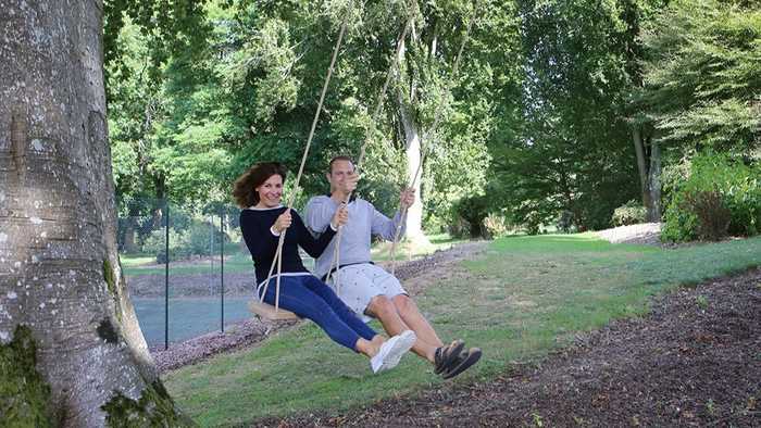Two adults swinging on tree rope swing