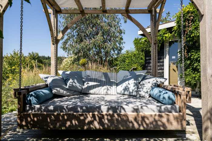 Day bed with drinks holders and cushions in dappled shade