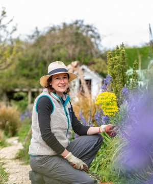 A smiling female gardener looking at the camera amongst garden foliage