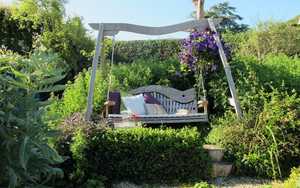 Curved Oak Swing Seat set amongst floral garden