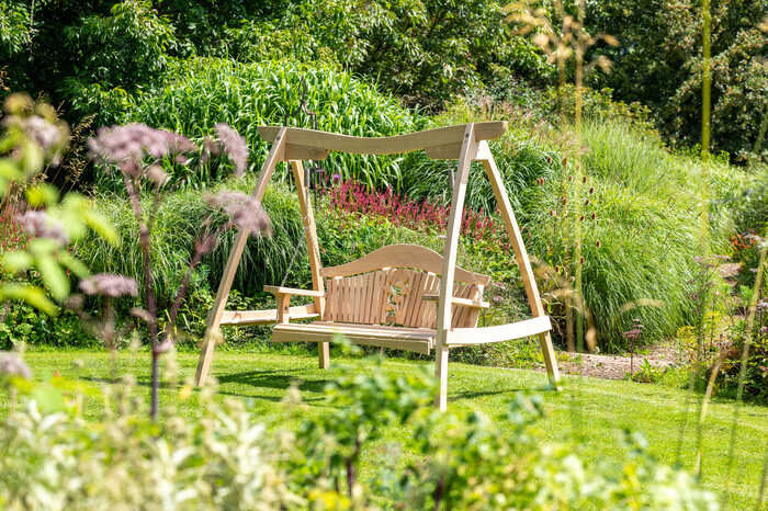 Oak swing seat in lush garden setting