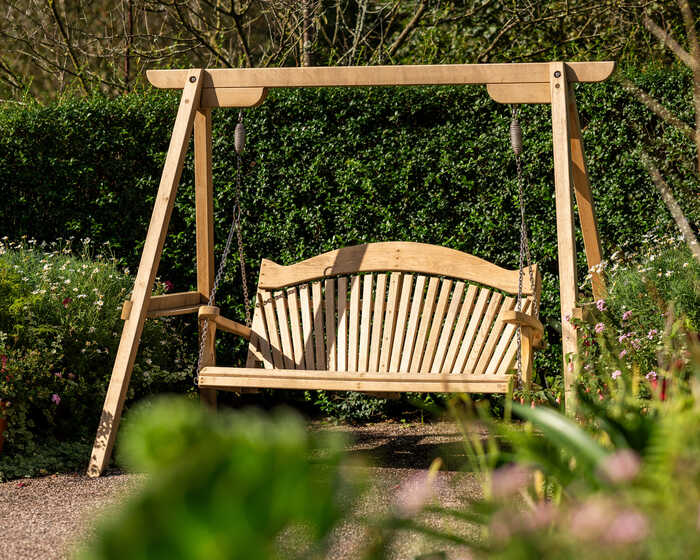 Wooden swing bench surrounded by colorful flowers and greenery.