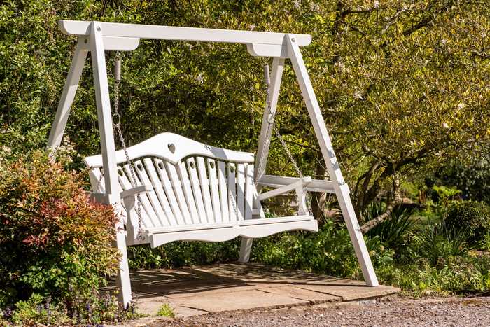 Painted swing seat set amongst shrubs