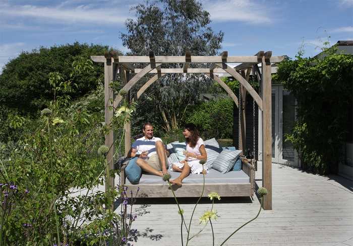 Family enjoying swinging day bed on decking Family enjoying swinging day bed on decking