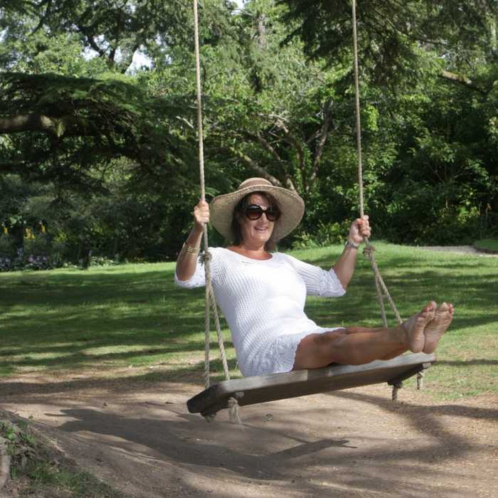 Mother and daughter swinging on a high quality swing seat hanging from a garden tree