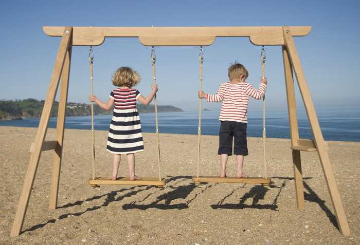 Two children on rope swings Lyme Regis beach 
