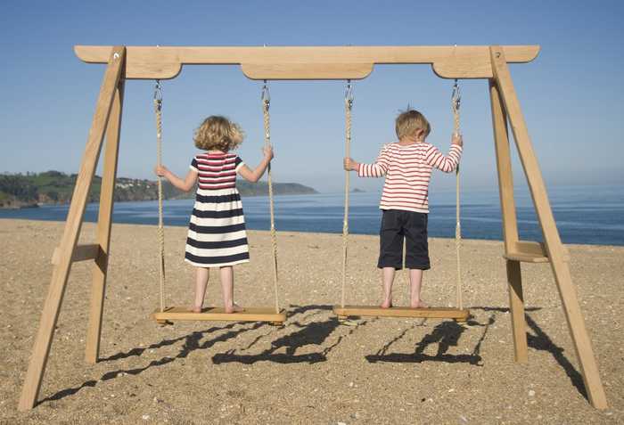 Two children on rope swings Lyme Regis beach