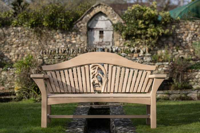 RHS Centenary Garden Bench in a garden with walled background
