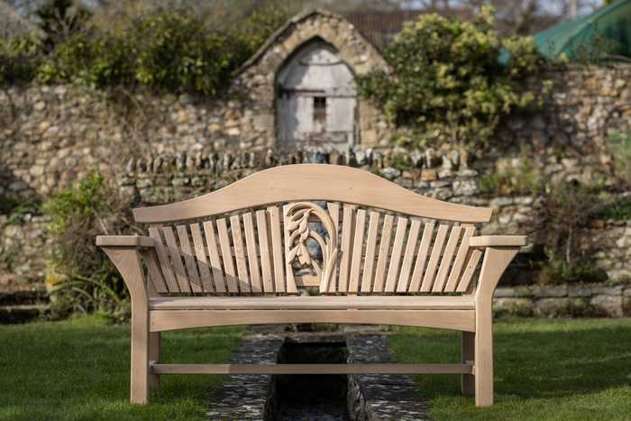 RHS Centenary Garden Bench in a garden with walled background 