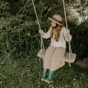 child with wellies on rope swing